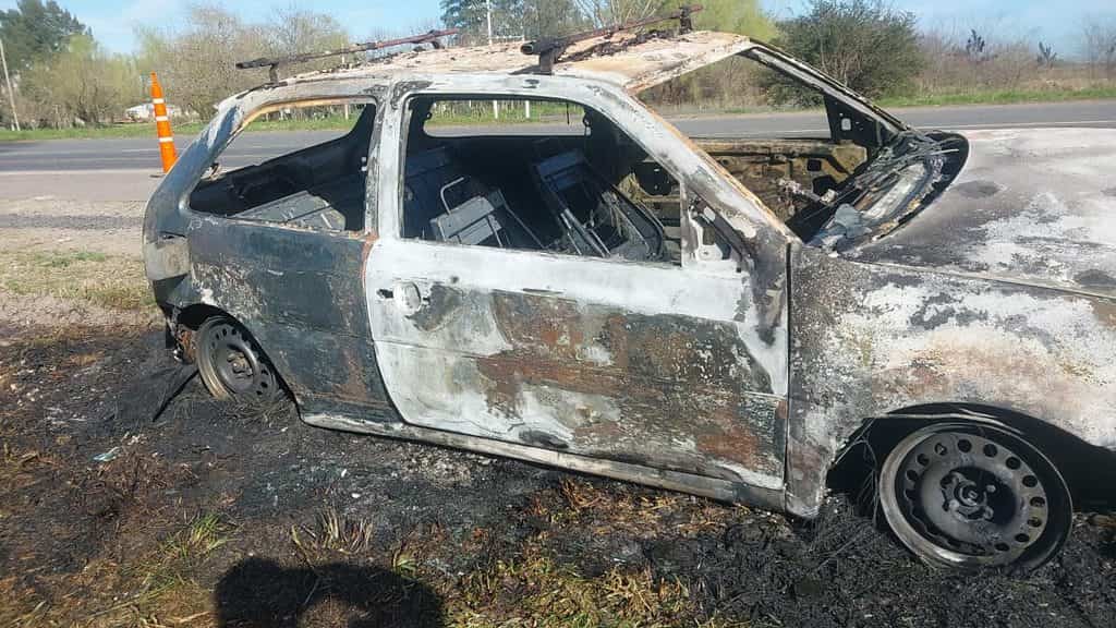 Detalle lateral del vehículo calcinado en la Ruta 3: carrocería quemada, interior destruido y cono de señalización visible al fondo