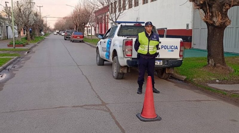 Policía bonaerense en control vial con cono de tránsito y patrullero en calle urbana de Alvear.
