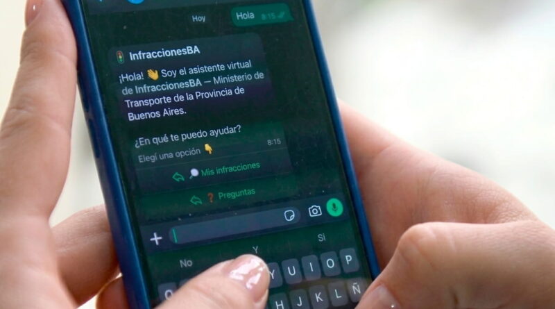 dos manos femeninas sostiene un celular. En pantalla se ve que esta haciendo una consulta sobre multas de tránsito en Whatsapp