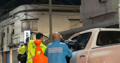 Agentes de seguridad vial controlan una camioneta blanca durante un operativo nocturno en una calle de Berisso, con un cono de tránsito en primer plano.