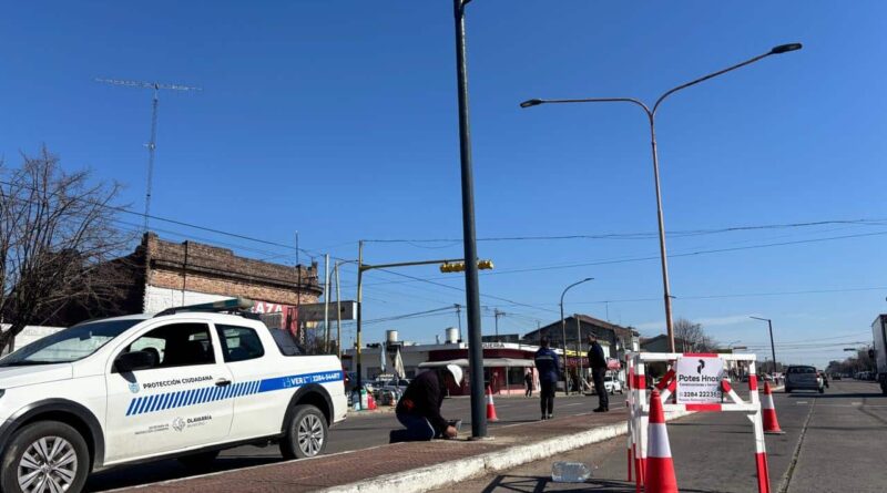 Trabajadores municipales instalan detectores de velocidad en una intersección de Olavarría, con cones de seguridad, vallas y una camioneta de Protección Ciudadana del Municipio de Olavarría custodiando la obra.