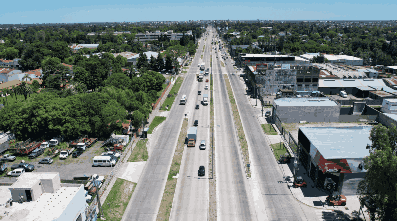 Toma aérea de la Ruta 4 con tránsito liviano atravesando zona urbana del conurbano bonaerense.